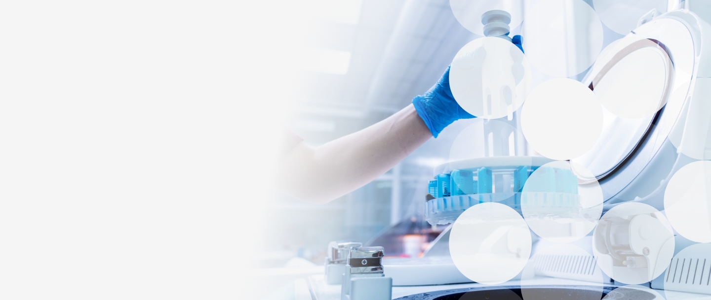 Hand in a blue surgical glove holding on to a piece of lab equipment in a lab